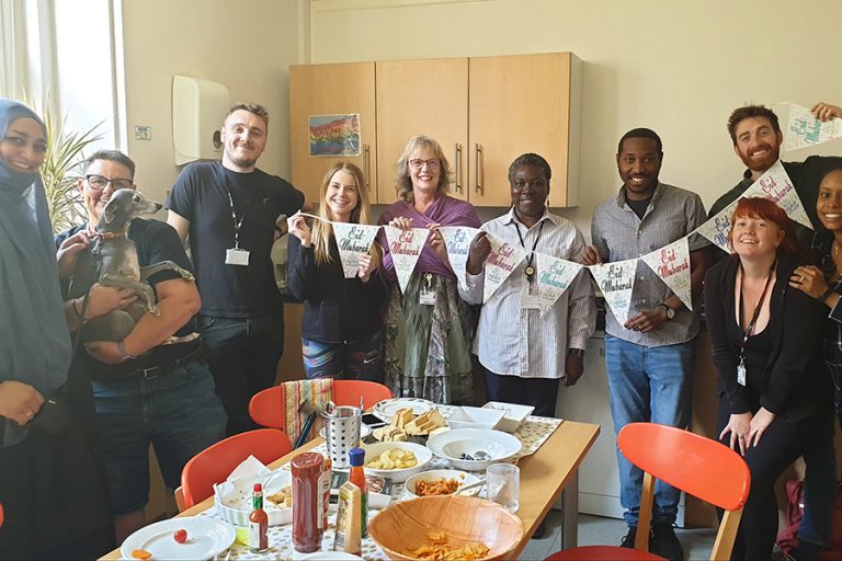 group of 8 people holding flag bunting round a table