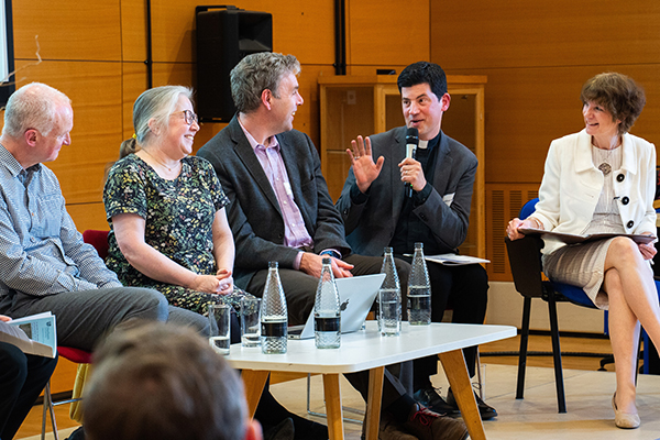 panel of seated adults listening to one man talk with a microphone.
